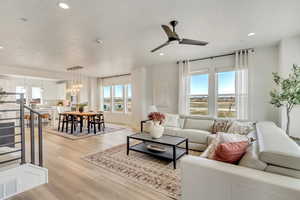 Living room with light hardwood / wood-style floors and ceiling fan with notable chandelier