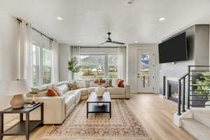 Living room with a healthy amount of sunlight, light wood-type flooring, and ceiling fan