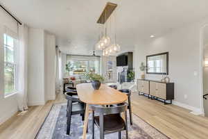 Dining area with an inviting chandelier, a healthy amount of sunlight, and light wood-type flooring