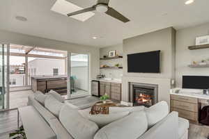 Living room with ceiling fan and light hardwood / wood-style flooring