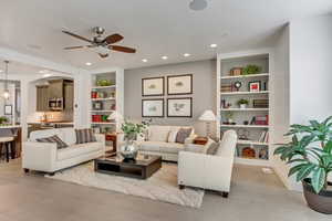 Living room featuring built in features, light tile patterned floors, a textured ceiling, and ceiling fan