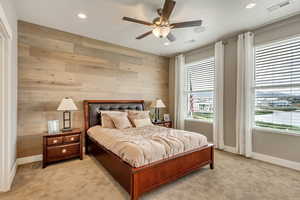 Carpeted bedroom with ceiling fan and wooden walls