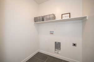 Laundry area featuring electric dryer hookup, dark tile patterned floors, and hookup for a washing machine