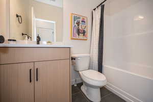 Full bathroom with shower / tub combo with curtain, vanity, tile patterned flooring, and toilet