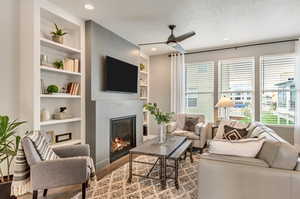 Living room featuring built in features, a textured ceiling, and ceiling fan