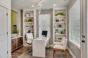 Home office featuring dark hardwood / wood-style floors and built in shelves