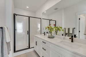 Bathroom featuring dual vanity, walk in shower, and tile patterned floors