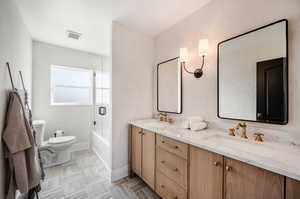 Full bathroom with bath / shower combo with glass door, toilet, tile patterned floors, and dual bowl vanity