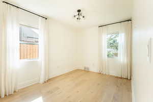 Empty room featuring an inviting chandelier and light hardwood / wood-style floors