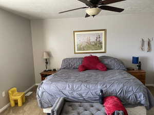 Bedroom with carpet flooring, a textured ceiling, and ceiling fan