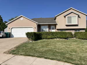 View of front of property with a garage and a front lawn