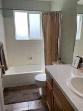 Full bathroom featuring vanity, shower / tub combo, toilet, and a wealth of natural light