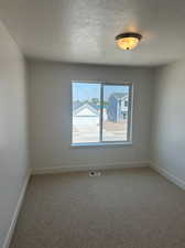 Unfurnished room with carpet and a textured ceiling