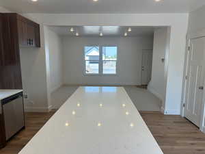 Kitchen featuring stainless steel dishwasher, light stone counters, and wood-type flooring