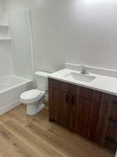 Full bathroom with hardwood / wood-style flooring, bathing tub / shower combination, toilet, and vanity