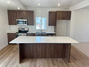 Kitchen featuring sink, a kitchen island, light wood-type flooring, and stainless steel appliances