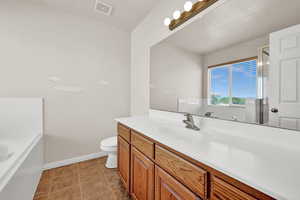 Bathroom featuring vanity, toilet, tile patterned floors, and a tub