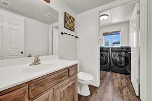 Bathroom featuring separate washer and dryer, a textured ceiling, toilet, vanity, and wood-type flooring