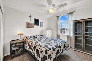 Bedroom with ceiling fan, lofted ceiling, and carpet flooring