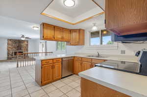 Kitchen with light tile flooring, sink, stainless steel appliances, a raised ceiling and a new window with farmhouse-style trim.