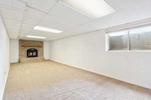 Unfurnished living room featuring a brick fireplace, light colored carpet, and a window.