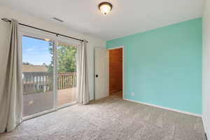 Bedroom or office with carpet and sliding glass door leading out to a Trex deck.