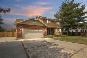 Twilight view of front property with a garage, RV parking and a lawn