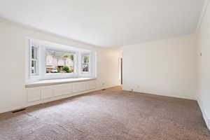 Living room with ornamental molding, light carpet and a custom window seat with views of Lone Peak.