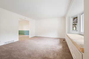 Living room with ornamental molding, light carpet and a custom window seat with views of Lone Peak.