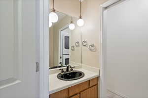 Half bathroom with stacked washer / dryer, tile floors, and vanity. Located on main level by entrance and stairs.