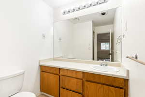 Primary bathroom featuring toilet, vanity and walk in shower.