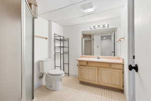 Spacious shared ensuite bathroom connecting two basement spare bedrooms, featuring tile flooring, a walk in shower, toilet, and vanity