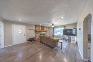 Living room with a brick fireplace, hardwood / wood-style floors, and a textured ceiling