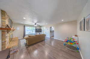 Living room with dark hardwood / wood-style flooring, a brick fireplace, and a textured ceiling