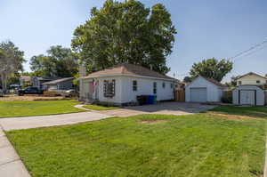 Single story home featuring a garage, a front lawn, and an outbuilding