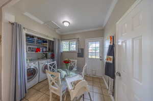 Tiled dining area featuring crown molding, washer and dryer, and a textured ceiling