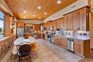 Kitchen with sink, decorative backsplash, stainless steel appliances, and light tile patterned floors