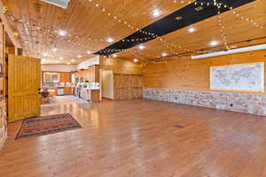 Entertainment room with wooden walls and light hardwood / wood-style flooring