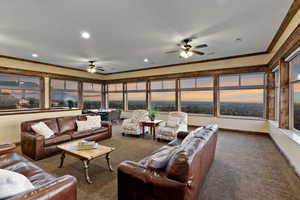 Carpeted living room with ceiling fan and crown molding