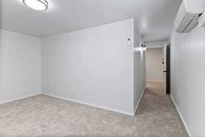 Unfurnished room featuring light colored carpet and a wall mounted air conditioner