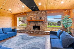 Entertainment room featuring wood-type flooring, wooden ceiling, a stone fireplace, and wooden walls