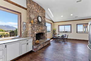 Living room with dark hardwood / wood-style floors, lofted ceiling, a stone fireplace, and a mountain view