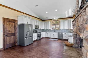 Kitchen with stainless steel appliances, dark hardwood / wood-style flooring, white cabinets, decorative backsplash, and lofted ceiling