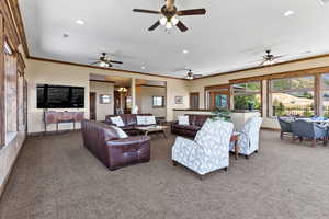 Living room featuring carpet flooring, crown molding, and ceiling fan