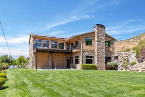 Back of house featuring a balcony and a yard