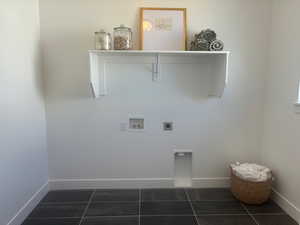 Washroom with electric dryer hookup, hookup for a washing machine, and dark tile patterned floors