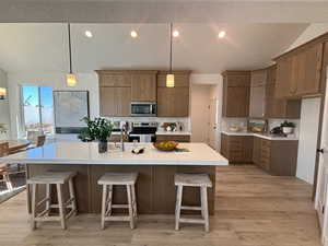 Kitchen featuring a center island with sink, light hardwood / wood-style flooring, a kitchen breakfast bar, and stove