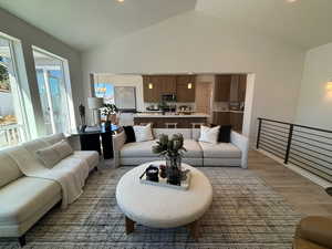 Living room featuring a notable chandelier, light wood-type flooring, high vaulted ceiling, and a textured ceiling