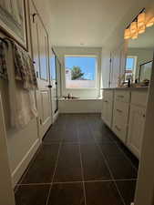 Bathroom featuring a textured ceiling, vanity, plus walk in shower, and tile patterned flooring