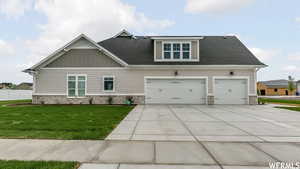 Craftsman-style home featuring a garage and a front lawn